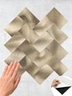 Hand applying a brass herringbone peel and stick tile sheet to a wall, demonstrating the easy DIY installation process.