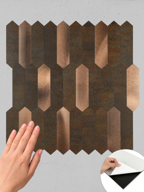 A hand removing the adhesive backing from a composite copper picket tile.