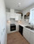 A bright utility room featuring tall and base cabinets flawlessly wrapped in Layed High Gloss White vinyl alongside a black washing machine and stainless steel sink.