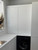 Close-up view of flat-panel kitchen cabinets completely transformed with Layed High Gloss White Vinyl Wrap, positioned above a black washing machine.