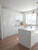 A contemporary kitchen space filled with natural light, highlighting the highly reflective finish of Layed High Gloss White Vinyl Wrap on the cabinets and center island.