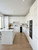 A compact, modern kitchen showcasing upper and lower cabinets upgraded with Layed High Gloss White Vinyl Wrap, contrasting beautifully with sleek black appliances.