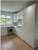 A spacious, bright galley kitchen featuring handleless cabinets and a large island, all wrapped in reflective Layed High Gloss White Vinyl Wrap.