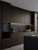 A contemporary kitchen featuring flat-panel cabinets finished in Java Walnut Wood Vinyl Wrap JWW99, paired with sleek black textured countertops and a matching dark backsplash.