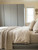 A cozy, sunlit bedroom setting featuring tall built-in wardrobes and a bed frame elegantly updated with Matte Textured Granite Grey Vinyl Wrap MTGG55, complementing the neutral, textured linen bedding.