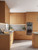A sunlit, contemporary kitchen showcasing flat-panel cabinets beautifully finished in Matte Textured Tuscan Terracotta Vinyl Wrap MTTT11, elegantly contrasted by light grey concrete countertops and built-in stainless steel ovens.
