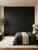 A modern, minimalist bedroom featuring a large, floor-to-ceiling built-in wardrobe flawlessly wrapped in Matte Textured Coal Black Vinyl Wrap MTCB83. The deep black finish contrasts beautifully with the room's warm neutral walls, natural wood flooring, and cozy bedding.