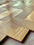 Macro detail showing the deep brushed metallic texture of the bronze metal herringbone composite wall tile next to a coin for scale.