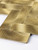 Macro detail showing the deep brushed metallic texture and rigid edge of the gold metal herringbone composite wall tile.
