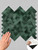 Hand touching the emerald herringbone composite wall tile.