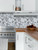 Kitchen setting featuring a stainless steel stove, wood countertops, white cabinets, and an aluminium herringbone composite tile backsplash.