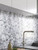 Modern kitchen counter featuring white cabinets, dark countertop, salt and pepper shakers, and a brushed aluminium herringbone tile backsplash.
