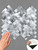 Hand touching the textured surface of a Layed brushed aluminium herringbone tile sheet, with an inset showing the peel-and-stick backing.