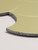 Macro close-up detailing the rigid composite edge and brushed metallic finish of the gold fan shaped peel and stick wall tile.