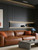 Contemporary living room showcasing a tan leather sofa and an LED-lit display shelf integrated into an ebony black slatted accent wall.