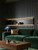 Luxurious living room featuring a green velvet sofa and an illuminated recessed display shelf built into an ebony black wood slatted wall.