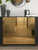 A modern black dresser featuring drawer fronts beautifully upgraded with Layed Chrome Mirror Gold Vinyl Wrap, showcasing its ultra-reflective, luxurious gold mirror finish in a stylish bedroom setting.