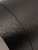 A macro close-up of Layed Black Leather Vinyl Wrap, highlighting the deeply embossed, highly realistic faux leather grain pattern and subtle sheen.