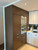 Tall kitchen cabinets featuring built-in ovens seamlessly upgraded using Layed Spiced Walnut Wood Vinyl Wrap, contrasting beautifully with modern white upper units.