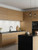 Modern kitchen cabinets fully modernized with Layed Natural Oak Wood Vinyl Wrap, contrasting beautifully with a white s backsplash and black countertops.