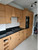 Traditional paneled kitchen cabinets fully modernized with Layed Natural Oak Wood Vinyl Wrap, contrasting beautifully with a white subway tile backsplash and black countertops.