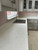 Detailed view of a stainless steel kitchen sink set into a bright, water-resistant countertop that has been transformed with Layed Bianco Marble Vinyl Wrap.