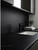 A sleek, dark modern kitchen workspace featuring a matte black faucet and continuous countertops and backsplash upgraded with Layed Royal Black Satin Marble Vinyl Wrap.