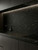 A luxurious dark kitchen illuminated by under-cabinet lighting, highlighting the smooth, satin black finish of Layed Royal Black Satin Marble Vinyl Wrap on the counters and backsplash.