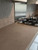 A close-up view of a kitchen countertop seamlessly wrapped in Layed Raw Concrete Vinyl Wrap, situated next to a stainless steel gas stovetop and a tiled backsplash.