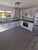 A bright kitchen featuring classic white cabinetry perfectly contrasted by a large center island and continuous countertops flawlessly upgraded with Layed Smoke Grey Concrete Vinyl Wrap.