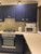 A modern kitchen featuring upper and lower cabinets beautifully transformed with Layed Brushed Metal Navy Blue Vinyl Wrap, paired perfectly with sleek silver hardware and light wood countertops.