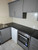Newly wrapped rock grey kitchen cabinets featuring silver knobs, a white countertop, and a textured stone backsplash, demonstrating the MTRG14 vinyl film.
