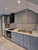 Newly wrapped rock grey kitchen cabinets featuring silver knobs, a white countertop, and a textured stone backsplash, demonstrating the MTRG14 vinyl film.
