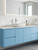 A bright, modern bathroom featuring a double sink vanity unit with cabinets flawlessly wrapped in Layed Matte Textured Sky Blue Vinyl Wrap, contrasting beautifully with a white countertop and vessel sinks.