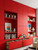 A modern children's playroom featuring extensive floor-to-ceiling built-in cabinets, drawers, and open shelving flawlessly wrapped in vibrant Matte Textured Rossa Corsa Red vinyl film.