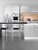 A contemporary kitchen space featuring lower and upper cabinets transformed with Satin Textured Silver vinyl wrap, paired with a glossy black countertop and modern white bar stools.
