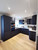 A modern U-shaped kitchen fully transformed with Layed Matte Silk Navy Blue Vinyl Wrap, featuring sleek built-in appliances and warm under-cabinet lighting.
