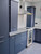 Kitchen base and upper cabinets modernized with Layed Matte Silk Navy Blue Vinyl Wrap, contrasting elegantly with a white marble tile backsplash and a stainless steel oven.
