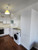 A functional utility or kitchen area showcasing tall cupboards and base units updated with Layed Matte Silk White Vinyl Wrap alongside a washing machine.