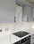 A modern kitchen backsplash flawlessly upgraded with Layed Calacatta White Marble Vinyl Wrap, contrasting beautifully with sleek grey upper cabinets.