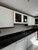 Close-up of kitchen cabinets beautifully wrapped in Layed Matte Silk Ivory vinyl, featuring contrasting dark wood trim and black countertops.