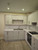 Upper and lower kitchen cabinets flawlessly updated with Layed Matte Silk Oat Vinyl Wrap around a stainless steel sink.