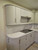 Close-up of curved kitchen cabinets wrapped in Layed Matte Silk Oat vinyl, featuring modern brushed metal handles.