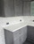 A contemporary kitchen showcasing upper and lower cabinets wrapped in Layed Grey Cement Vinyl Wrap, perfectly contrasted with bright white marble countertops.
