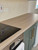 Close-up of a kitchen countertop seamlessly covered in Layed Washed Oak Wood Vinyl Wrap, showing a professional finish next to a black glass stovetop.