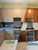 A striking before and after comparison of a kitchen transformed from dark, dated wood cabinets to a bright, modern aesthetic using Layed Washed Oak Wood Vinyl Wrap.