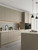 A bright, modern kitchen featuring sleek, flat-panel wall and base cabinets completely transformed using Layed Painted Wood Tan Vinyl Wrap, paired with matte black fixtures.