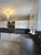 A beautiful kitchen featuring classic white shaker cabinets and a deep farmhouse sink, flawlessly complemented by Layed Lombarda Grey Marble Vinyl Wrap on the counters and backsplash.