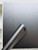A roll of Layed Brushed Metal Titanium Vinyl Wrap resting against a modern cabinet door that has been seamlessly wrapped in the exact same dark metallic film.