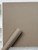 A roll of Layed Caramel Fabric Vinyl Wrap resting against a flat display panel that has been seamlessly wrapped in the exact same cozy, textured film.